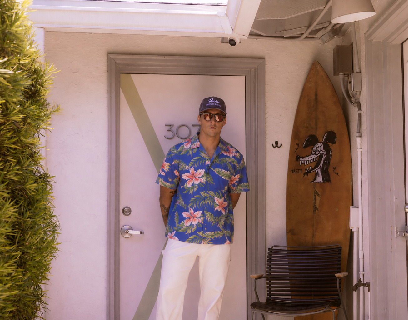 Duvin floral shirt and cap worn beside a surfboard