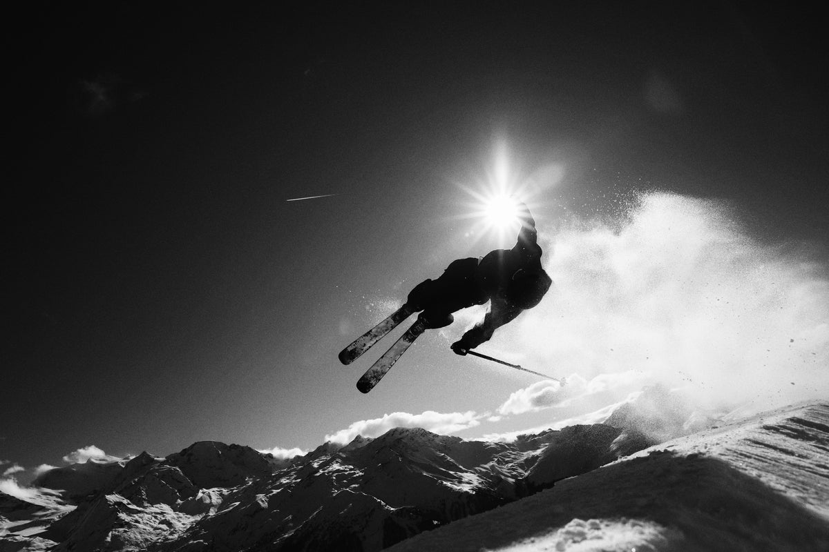 A skier airborne above the mountains with Kang poles